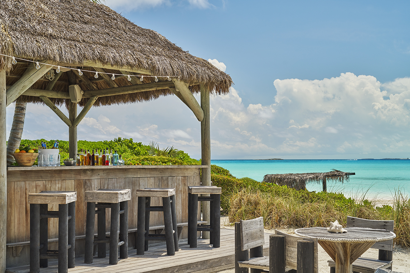 a cabana bar with palm trees and a beach and sky
