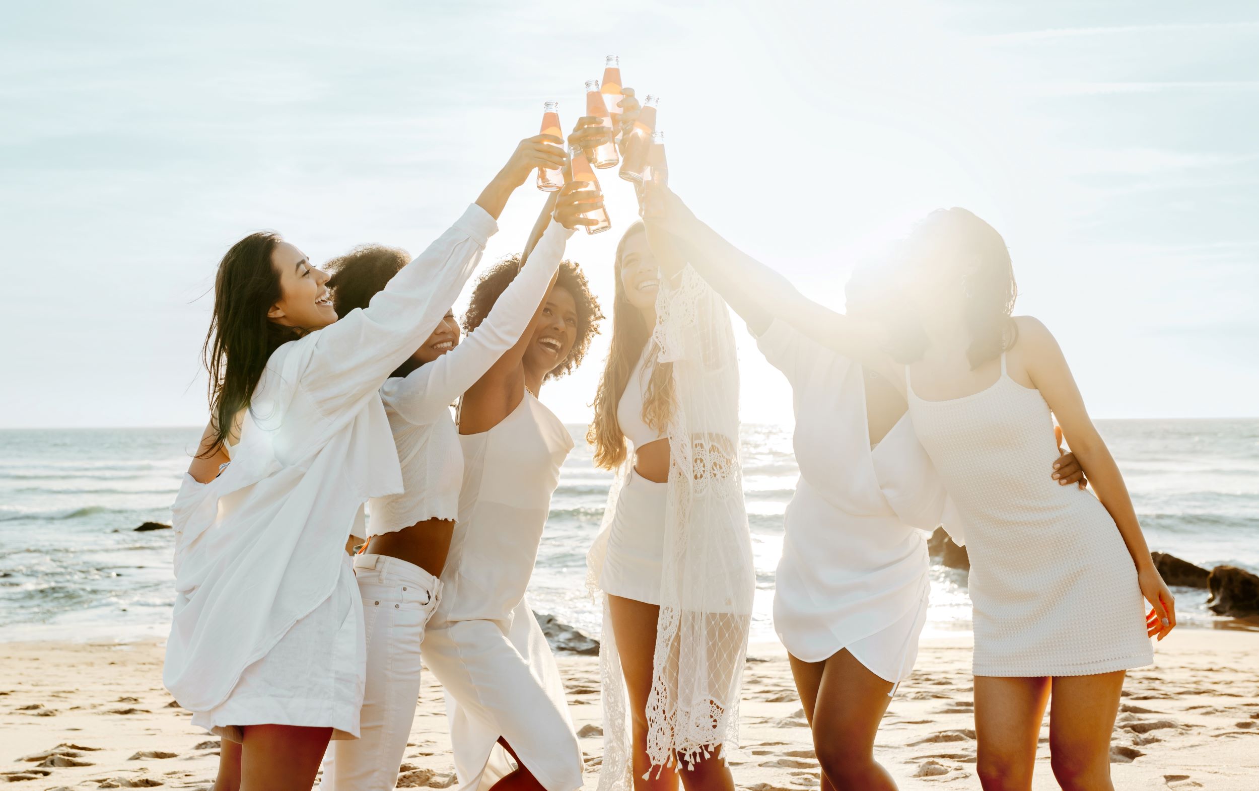 a group of women in white holding up drinks